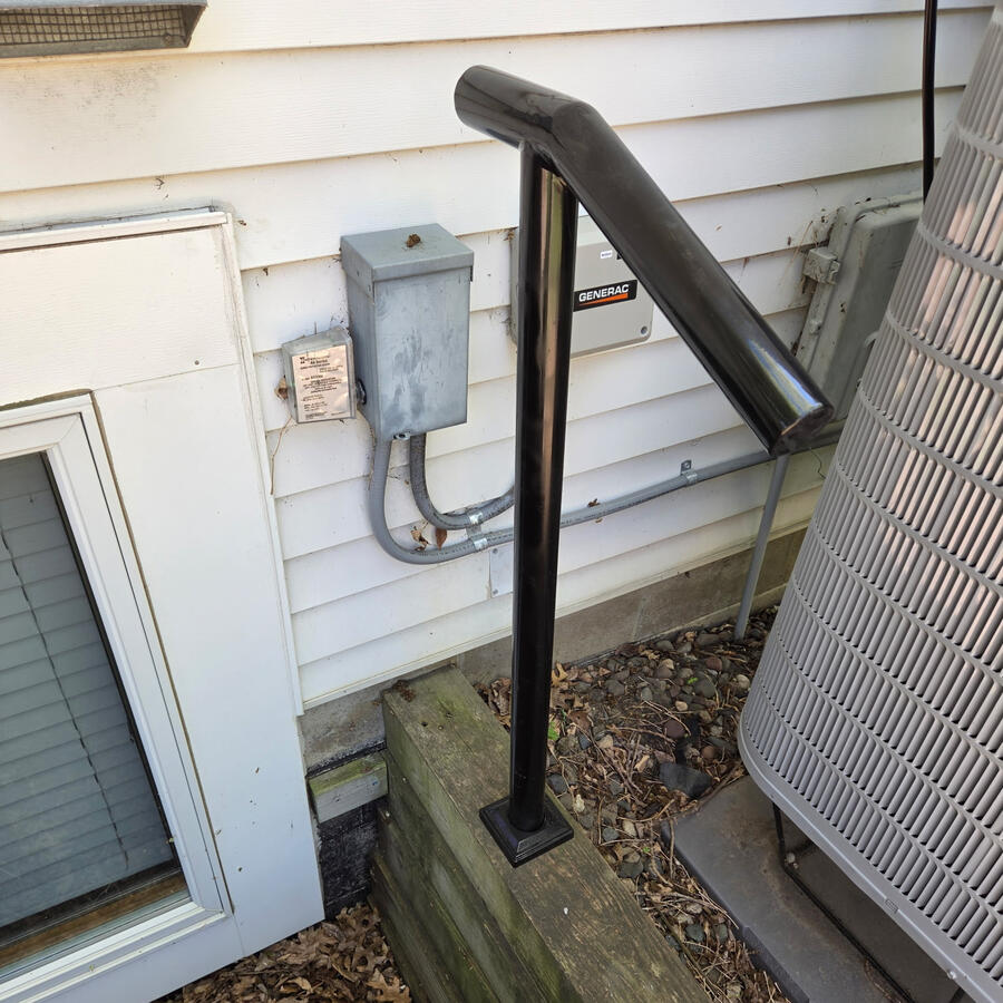 A sturdy support rail added to make accessing a hard-to-reach hose spigot safer and more stable.